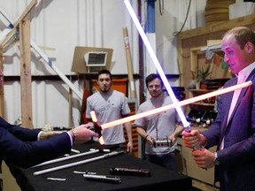 Britain's Prince William, right, and Prince Harry use light sabres during a tour of the Star Wars sets at Pinewood studios in Iver Heath, west London, Tuesday April 19, 2016. Prince William and Prince Harry toured Pinewood to visit the production workshops and meet the creative teams working behind the scenes on the Star Wars films. (Adrian Dennis/Pool via AP)