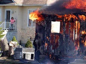 A girl looks on, as a house burns down on Danshab Road on Walpole Island on Saturday, April 16. The house, which was abandoned, was used by the Walpole Fire Department during the day for training exercises.