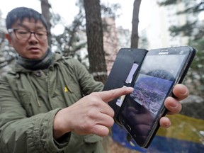 In this Jan. 28, 2016, photo, Choi Seung-woo shows an old photo of the Brothers Home, a mountainside institution where some of the worst human rights atrocities in modern South Korean history took place, in Busan, South Korea. An Associated Press investigation found that rapes and killings of children and the disabled three decades ago at a South Korean institution for so-called vagrants, the Brothers Home, were much more vicious and widespread than previously realized. (AP Photo/Ahn Young-joon)