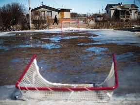 A manwalks along the road as the snow and ice melts on an outdoor hockey rink in the northern Ontario First Nations reserve in Attawapiskat, Ont., on Tuesday, April 19, 2016. THE CANADIAN PRESS/Nathan Denette