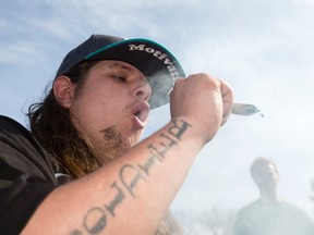 A man smokes a marijuana cigarette at a table in Victoria Park as pot advocates celebrate "420" in the downtown park in London, Ont. on Wednesday April 20, 2016. Craig Glover/The London Free Press/Postmedia Network