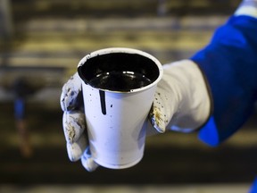 A worker holds a cup of heavy oil before it is shipped to the market at the Cenovus Energy Christina Lake Steam-Assisted Gravity Drainage (SAGD) project 120 km (74 miles) south of Fort McMurray, Alberta, in this August 15, 2013 file photo. (REUTERS/Todd Korol/Files)