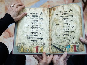 In this photo taken Wednesday, April 13, 2016, Eli and Shuli Barzilai holds a copy of the Birds' Head Haggadah in his house in Jerusalem. Barzilai and his cousins, family grandchildren of one of the earliest Jewish victims of the Nazis are laying claim to a jewel of Israel's leading museum: the world's oldest surviving illustrated Passover manuscript.  (AP Photo/Dan Balilty)