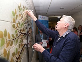 Ian Davis-Young along with his wife Judy place a sticker with their son Gavin's name on a Organ Donation Memorial wall at Kingston General Hospital on Thursday April 21 2016. Ian MacAlpine /The Whig-Standard/Postmedia Network