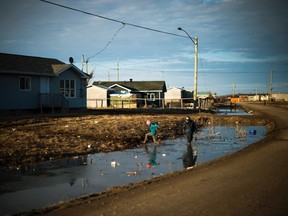 Indigenous children play in the water filled ditches in the northern Ontario First Nations reserve in Attawapiskat, Ont., on Tuesday, April 19, 2016. THE CANADIAN PRESS/Nathan Denette