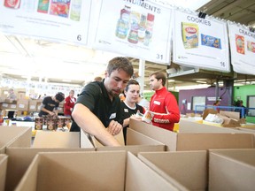 Canadian Olympian Jason Myslicki packs non-perishable items along with other volunteers on Oct. 12, 2013 as part of the Thanksgiving Drive at the Daily Bread Food Bank in Toronto. (Veronica Henri/Toronto Sun)