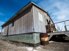 Teresa Kataquatit, 75, stands on the porch of her home which has been deemed not fit for human habitation in the northern Ontario First Nations reserve in Attawapiskat, Ont., on Wednesday, April 20, 2016. THE CANADIAN PRESS/Nathan Denette