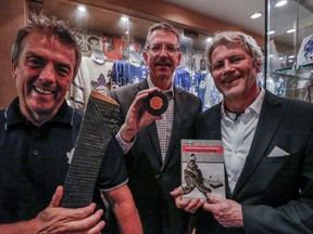 Dan Donohue (centre) holds up the puck that Bill Barilko scored with for the Leafs against Montreal during OT in 1951. To his left is David McNeil, son of David McNeil who was in goal for the Habs that night, and on his right is Mike Wilson, who's home is known as the ultimate Leaf fan, in Toronto on Thursday April 21, 2016. (Dave Thomas/Toronto Sun)