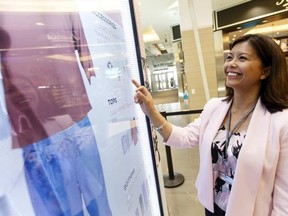 Claire Kolmatycki, marketing director with Southgate Centre, demonstrates the new My Virtual Look interactive display in Edmonton on Thursday. Shoopers are able to swipe 150 items to digitally dress a physical mannequin. Ian Kucerak / Postmedia