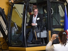 David Eggen, Minister of Education, poses for a photo in an excavator at the official opening of NAIT's new Heavy Equipment Technology Building. (Ed Kaiser photo)