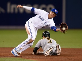 Athletics baserunner Chris Coghlan slides safe into second base on a passed ball as Blue Jays' Darwin Barney makes a catch during sixth inning MLB action in Toronto on Friday, April 22, 2016. (Frank Gunn/THE CANADIAN PRESS)
