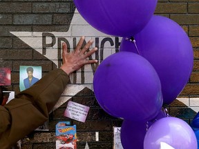 A mourner and fan touches the star for Prince on a wall at First Avenue where the singer often performed, Saturday, April 23, 2016, in Minneapolis. The pop superstar died Thursday at the age of 57. (Jim Gehrz /Star Tribune via AP)