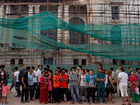 Nepalese people stand near a damaged heritage building as they prepare to light candles in memory of those who died in last year's devastating earthquake in Basantapur Durbar Square in Kathmandu, Nepal, Sunday, April 24, 2016. Nepalese held memorial services to mark the anniversary of the disaster that killed nearly 9,000 people and left millions homeless. (AP Photo/Niranjan Shrestha)