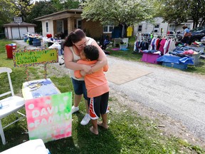 In this April 22, 2016 photo, Donnie Davis gives Tristan Jacobson a kiss outside their home in Springfield, Mo. Tristan has been living with with Donnie and Jimmy Davis, who have been Tristan's kinship guardians. They have been holding a yard sale and set up a lemonade stand to raise money for his adoption. (Andrew Jansen/The Springfield News-Leader via AP)