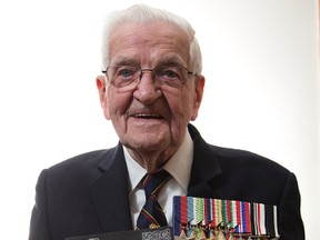 London vet Bob Kennedy, 95, holds a photo of himself at 17 in Royal Marine uniform. He recently received Russia?s Ushakov Medal, left, for bravery during the Second World War. (DEREK RUTTAN, The London Free Press)