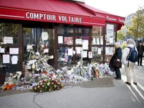 People stop to look at flowers, candles and messages left in tribute to victims in front of the Comptoir Voltaire cafe, one of the sites of the deadly attacks in Paris, France, on Nov. 21, 2015. (REUTERS/Charles Platiau)