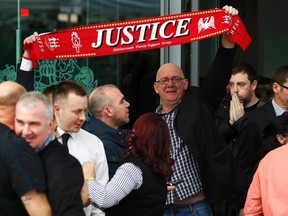 Relatives hold up a scarf after the jury delivered its verdict at the new inquests into the Hillsborough disaster in Warrington, England April 26, 2016. (REUTERS/Phil Noble)