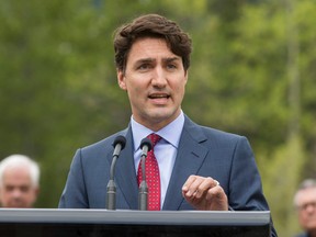 Prime Minister Justin Trudeau speaks to media in front of his cabinet after a string of meetings at the Delta Lodge at Kananaskis west of Calgary, Alta., on Tuesday, April 26, 2016. The federal Liberal cabinet was wrapping up three days of meetings at the lodge. Lyle Aspinall/Postmedia Network