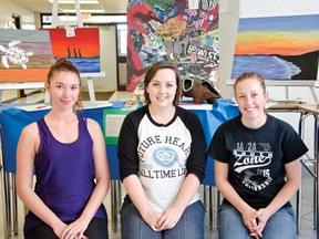 Nicole Davis, left, Hayley Davis, and Megan McGlynn, right, stayed after school on Thursday night to auction off student-produced artwork to buy goats for third world countries. | Caitlin Clow photos/Pincher Creek Echo
