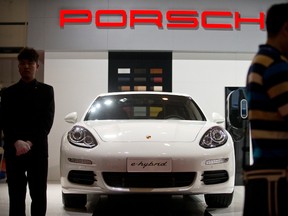 A staff member stands next to a Porsche Panamera S E-Hybrid on display at the Beijing International Automotive Exhibition in Beijing, Monday, April 25, 2016. (AP Photo/Mark Schiefelbein)