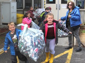 Teacher Helen Ellsworth looks on as her Grade 1 students from Holy Family Catholic School on Wiley Street carry some of the more than 2,000 pop cans they collected as an Earth Day project. The money from the cans will go to Habitat For Humanity projects. (Michael Lea/The Whig-Standard)