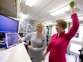Heart transplant recipient Ellen Desrosiers, seen at left on monitor, who is completing a physio program following her successful surgery last September, lifts weights Tuesday under instruction from Multi-Organ Transplant Program physiotherapist Nancy Howes, far right, as physiotherapy associate Tracy Fuller takes notes at University Hospital. (CRAIG GLOVER, The London Free Press)