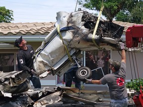 Salvage crews use a crane, Tuesday, April 26, 2016, to remove the wreckage of a plane that crashed into a home in Pompano Beach, Fla. Officials say three people were injured when their small plane crashed, no one inside the house was injured. (Joe Cavaretta/South Florida Sun-Sentinel via AP)