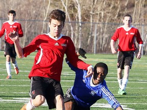 Gino Donato/Sudbury Star
James Pinheiro of the St. Benedict Bears gets tripped up while fighting for the ball with John Squarzolo of the St. Charles Cardinals during senior boys soccer action at James Jerome Feild on Tuesday.