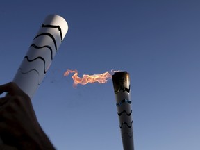 Syrian refugee Ibrahim al-Hussein, an amputee swimmer, prepares to handover the Olympic Flame to Spiros Kalozoumis, during the Olympic Flame torch relay at the Eleonas refugee camp in Athens, Greece on April 26, 2016. (REUTERS/Alkis Konstantinidis)