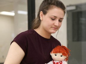 Tim Miller/The Intelligencer
Student Mikaela Lahn speaks with a volunteer during a poverty challenge at Loyalist College on Wednesday in Belleville. The doll indicates the profile she is role-playing has a child that could be taken away as part of the challenge.