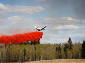 An Alberta Forestry Tanker drops fire retardant on the trestle bridge fire that caused a critical railway line to collapse on Tuesday April 28, 2016.