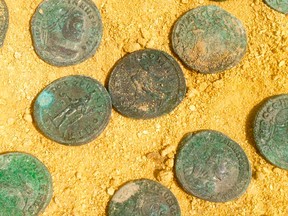 This photo made available by the City Council of Tomares on Friday, April 29, 2016, shows some of the bronze and silver-coated coins dating from the end of the 4th century. Workers laying pipes in a southern Spanish park have unearthed a 600-kilogram (1,300-pound) trove of Roman coins in what culture officials say is a unique historic discovery. (City Council of Tomares via AP)