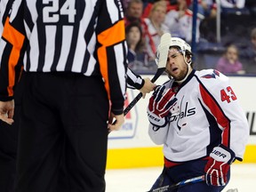 An official removes a stick from the face shield of Washington Capitals' Tom Wilson during the second period of an NHL hockey game against the Columbus Blue Jackets in Columbus on Jan. 2, 2016. (AP Photo/Jay LaPrete)