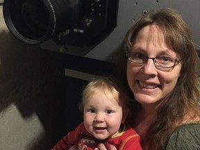 Joanne Struss, with her youngest son, Luke, next to their newly acquired digital projector. Joanne and her husband, Darren Struss, of Killarney purchased the projector in order to keep their Shamrock Drive-In running as movies are no longer available in 35 mm film.