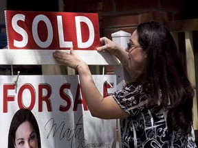 A real estate agent puts up a "sold" sign in front of a house in Toronto Tuesday, April 20, 2010. (THE CANADIAN PRESS/Darren Calabrese)