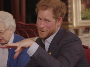 This image taken from a video released by Kensington Palace, London, on Friday April 29, 2016 shows Queen Elizabeth II sitting with her grandson, Prince Harry as he says "Boom" whilst receiving a video call from the President of the United States, Barack Obama and Michelle Obama. Prince Harry, released the video Friday promoting the upcoming Invictus Games for wounded veterans. The cast includes his grandmother Queen Elizabeth II, and Barack and Michelle Obama, who Harry had over for dinner last week. The video starts with Harry and the queen looking at an Invictus brochure when they get a video phone message from Mrs. Obama. (@KENSINGTONROYAL via AP)