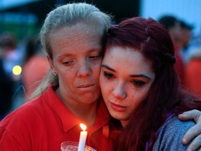 Amber Cassell, 16, right, gets a hug from Margaret Williams, left, as they hold a candle into the air during the Pike County Vigil at the Pike County  Fairgrounds in Piketon, Ohio on Friday, April 29, 2016. (Kyle Robertson/The Columbus Dispatch via AP)