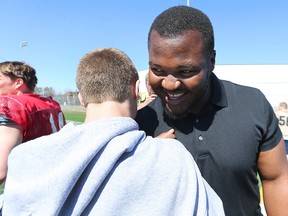 David Onyemata is congratulated by a former teammate at the University of Manitoba Bisons practice facility in Winnipeg on April 30, 2016. (Kevin King/Winnipeg Sun/Postmedia Network)
