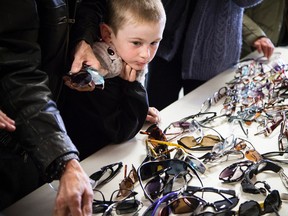 Drake Fischer-Wiskin, 6, took a good look through the shades at the OC Transpo unclaimed items sale. Ashley Fraser Postmedia