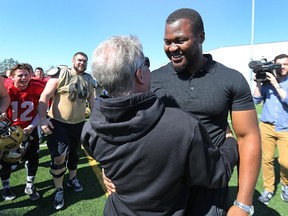 David Onyemata hugs former coach Brian Dobie as his former teammates rush in to congratulate him at the University of Manitoba Bisons practice facility in Winnipeg on Sat., April 30, 2016. Onyemata was selected in the fourth round by the New Orleans Saints, becoming the first Bison to be selected in the NFL draft. (Kevin King/Winnipeg Sun/Postmedia Network)