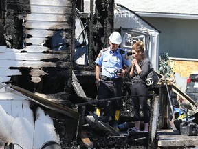 A fire investigator speaks with resident Kayla Tousignant after a fire broke out at a triplex on Manitoba Avenue in Winnipeg on Sunday, May 1, 2016. Nine people were able to escape with one woman suffering from smoke inhalation. (Kevin King/Winnipeg Sun/Postmedia Network)