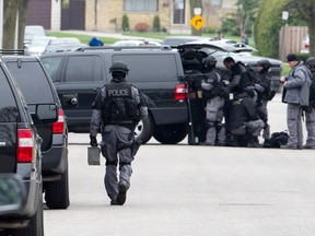 Members of the London Police emergency response unit assemble on Cecilia Avenue in London, Ont. on Sunday May 1, 2016. The tactical responders were seen entering a duplex on the street wearing gas masks before firing tear gas into the home. (CRAIG GLOVER, The London Free Press)