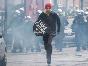 An anti-capitalist demonstrator runs from police during a May Day protest in Montreal, Sunday, May 1, 2016. THE CANADIAN PRESS/Graham Hughes