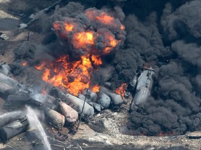 Smoke rises from railway cars that were carrying crude oil after derailing in downtown Lac-Megantic, Que., on July 6, 2013. The federal government quietly spent $75 million to settle with victims and creditors affected by the Lac-Megantic rail disaster -- a contribution that also shielded it from lawsuits related to the deadly crash. (THE CANADIAN PRESS/Paul Chiasson)