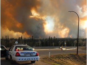 RCMP manning a blockade across from Mackenzie Blvd. on Highway 63 as smoke from the city's second wildfire of the day makes it way over the valley. Stephanie Jellett/ Fort McMurray Today/ Postmedia Network