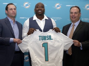 Offensive lineman Laremy Tunsil (centre) holds a jersey during a news conference as Dolphins head coach Adam Gase (left) and Executive Vice President for Football Operations Mike Tannenbaum (right) look on in Davie, Fla., on Friday, April 29, 2016. Tunsil was drafted by the Dolphins in the first round of the NFL draft. (Lynne Sladky/AP Photo)
