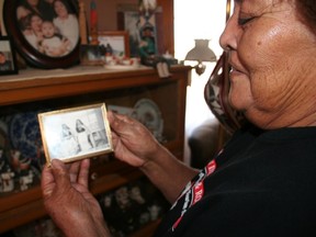This November 2014 image provided by the American Indian Alaska Native Tourism Association shows Mary Lowden holding a photo of her mother and her aunt, both pottery makers, during a visit to her home at Acoma Pueblo, N.M. The pueblo is among the tribal communities featured in a new guidebook titled "American Indians & Route 66." Lowden said as a girl, she and her sisters would walk down to the highway to sit at the general store and sell the pottery they helped make.  (Lisa Snell/American Indian Alaska Native Tourism Association via AP)