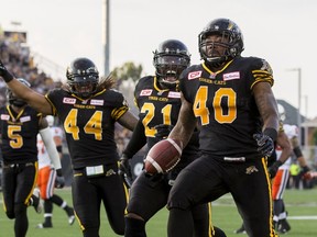Tiger-Cats defensive end Eric Norwood (right) returns a fumble for a touchdown as teammates Simoni Lawrence (21) and Taylor Reed (44) celebrate during CFL action against the Lions in Hamilton, Ont., on Aug. 15, 2015. The Ticats released 11 players, including Norwood, on Tuesday. (Mark Blinch/Reuters/Files)