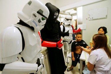 Members of a Star Wars fan club in Thailand, dressed as Kylo Ren (in black) and Stormtroopers (white), cheer a boy as a doctor checks him during Star Wars Day celebration at the Queen Sirikit National Institute of Child Health in Bangkok, Thailand, May 4, 2016. REUTERS/Chaiwat Subprasom