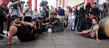 A fan, left, teaches a fan dressed as a Star Wars character how to pose for a photo call as they cerebrate the Star Wars Day in Taipei, Taiwan, Wednesday, May 4, 2016. May 4 is known as Star Wars Day among fans worldwide since the date sounds phonetically similar to the franchise's slogan: "May the Force Be With You." (AP Photo/Chiang Ying-ying)